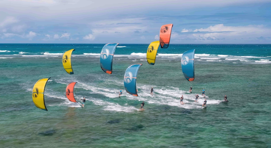 Kiters in azione sulle onde con kite colorati in un paesaggio marino